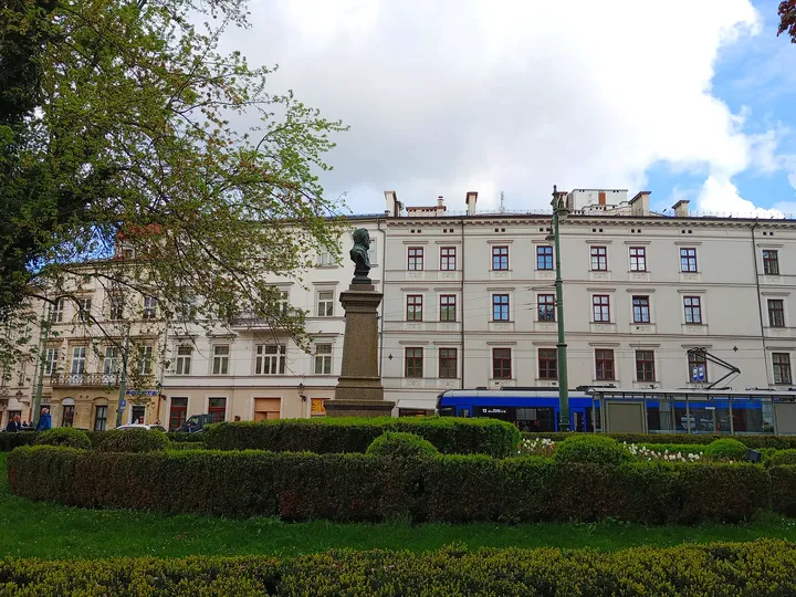 Palace beyond clipped garden beds at All Saints Square, Kraków