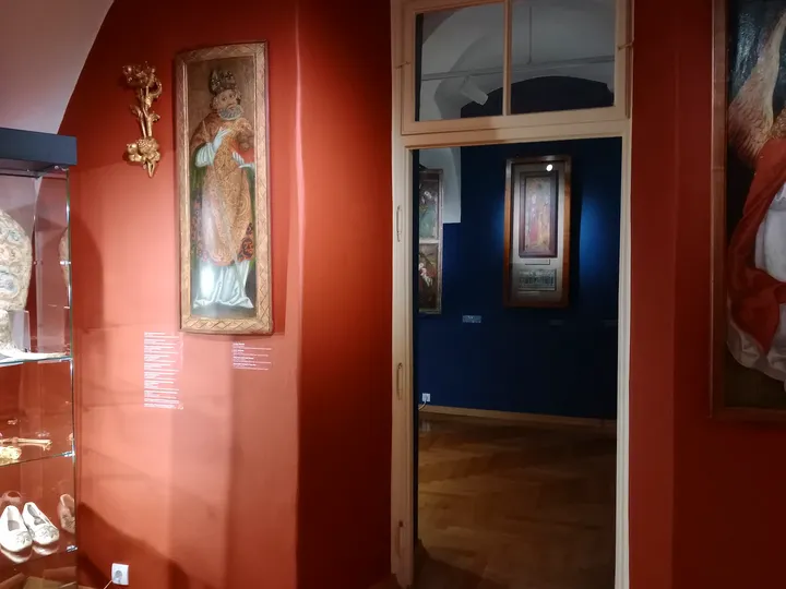 Paintings in a red-walled gallery at Archdiocesan Museum, Kraków
