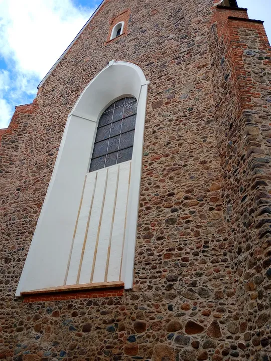 A tall pointed window in the exterior wall at Assumption Church, Żagań