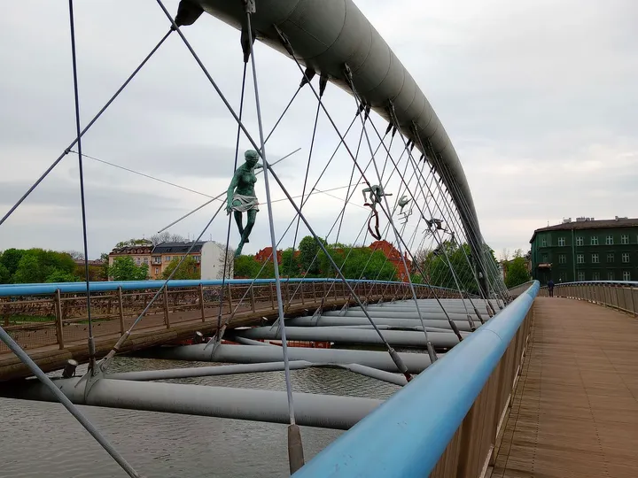 Suspended figures along the footbridge at Between Water and Sky sculptures