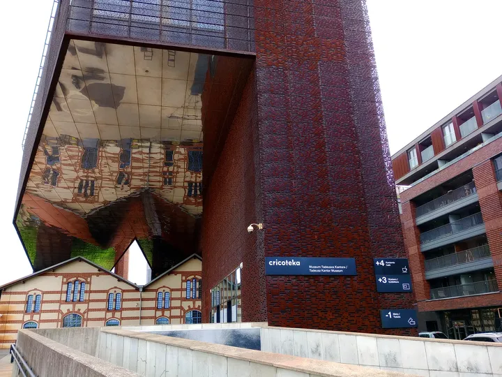 Street approach beneath the large mirror surface at Cricoteka