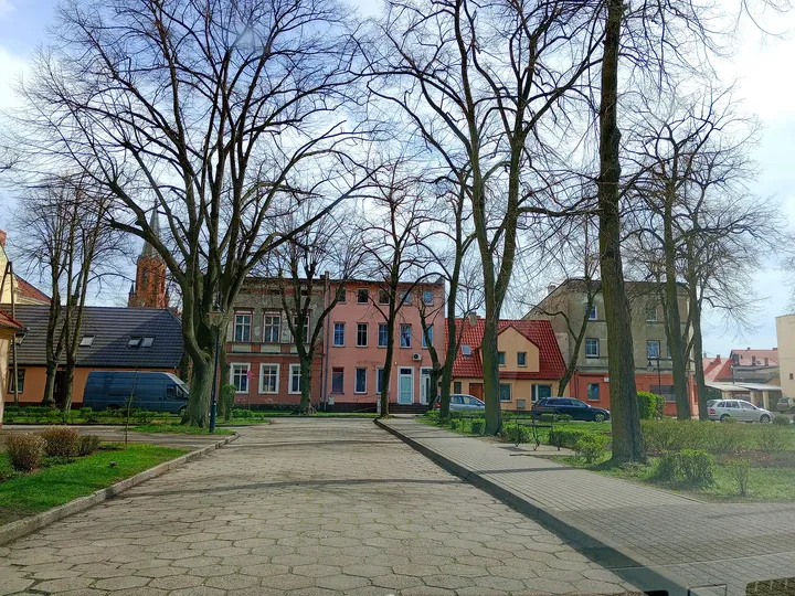 Low brick building beyond the trees at Czerwieńsk town walk