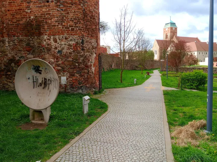 A stone millwheel beside the brickwork at General Maczek Square, Żagań
