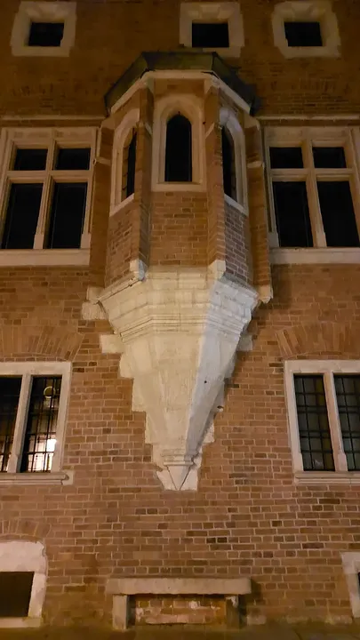 A stepped brick façade lit at night at Gołębia Street