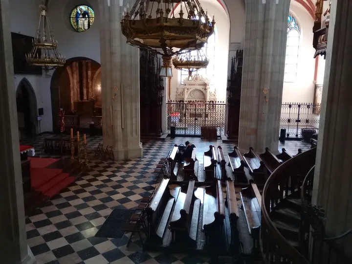 The tiled aisle and dark pews at Holy Trinity Basilica, Kraków