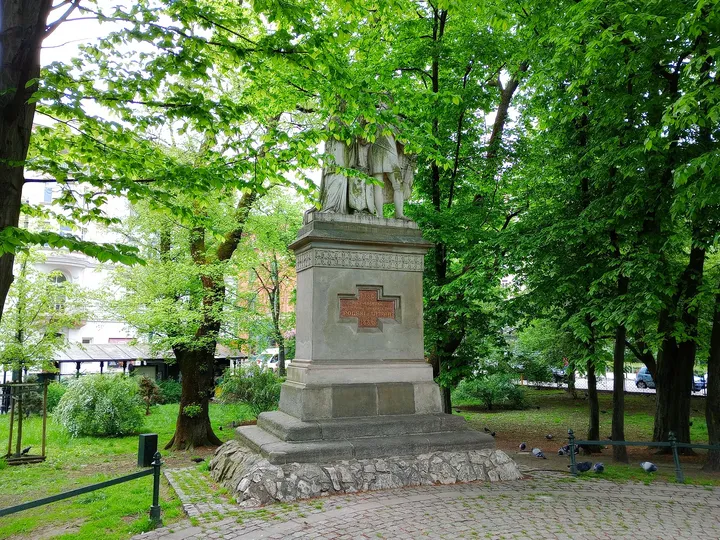 The sculpted figures beneath the tree canopy at Jadwiga and Jagiełło monument
