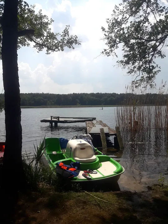Boats beneath the shoreline trees at Lake Sławskie