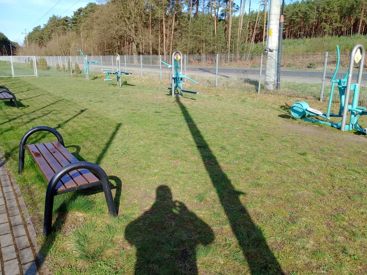 Outdoor fitness equipment beside the fenced field at Łężyca outdoor exercise ground