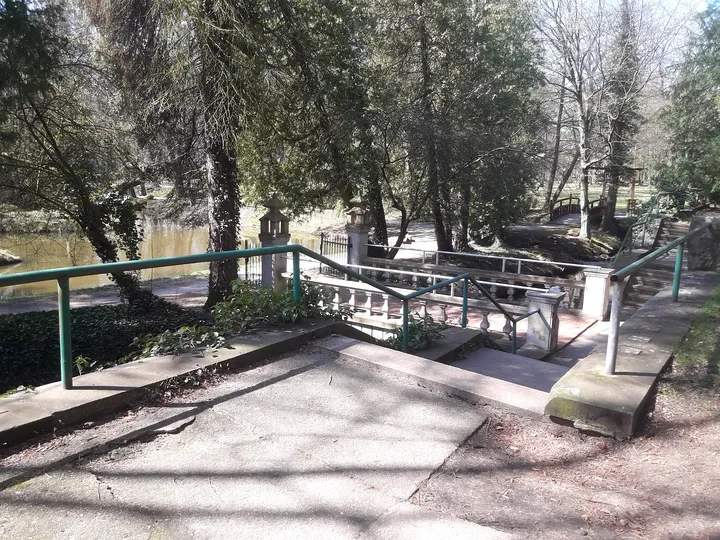 The paved approach beneath bare branches at Manor Park, Iłowa