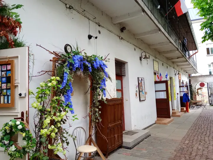 A doorway beneath hanging flowers at Mleczarnia courtyard