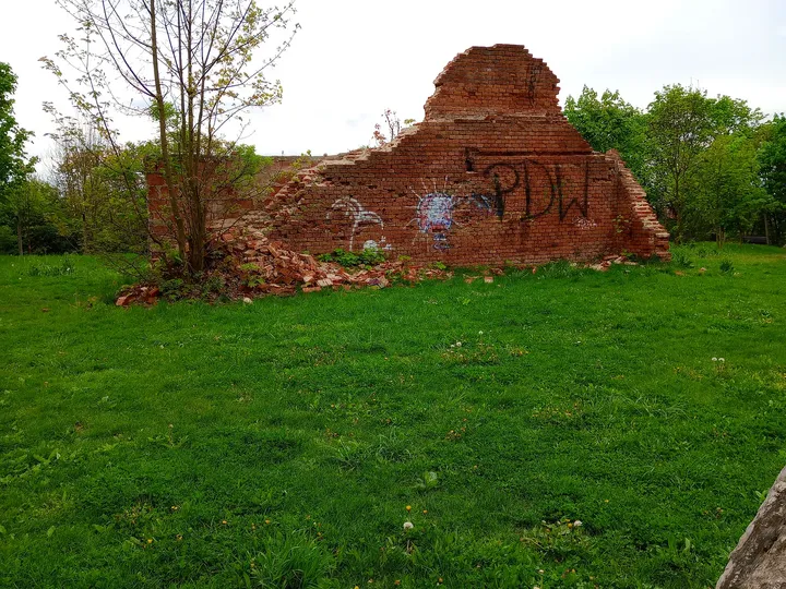 Brick remains beyond the lawn at Peace Bells Garden, Kraków