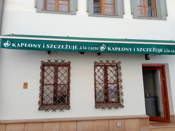 Windows beneath a green storefront sign at Plac Izaaka street food square