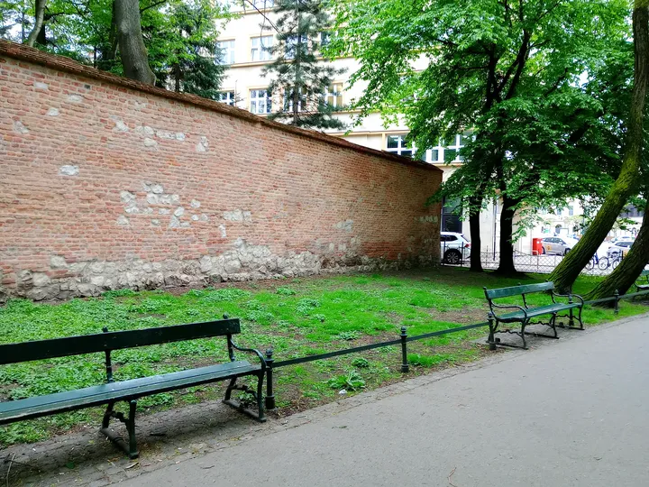 Benches beside an old brick wall at Planty: Florianka Garden