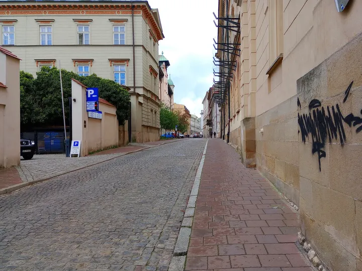 The paved lane beside a high wall at Poselska Street