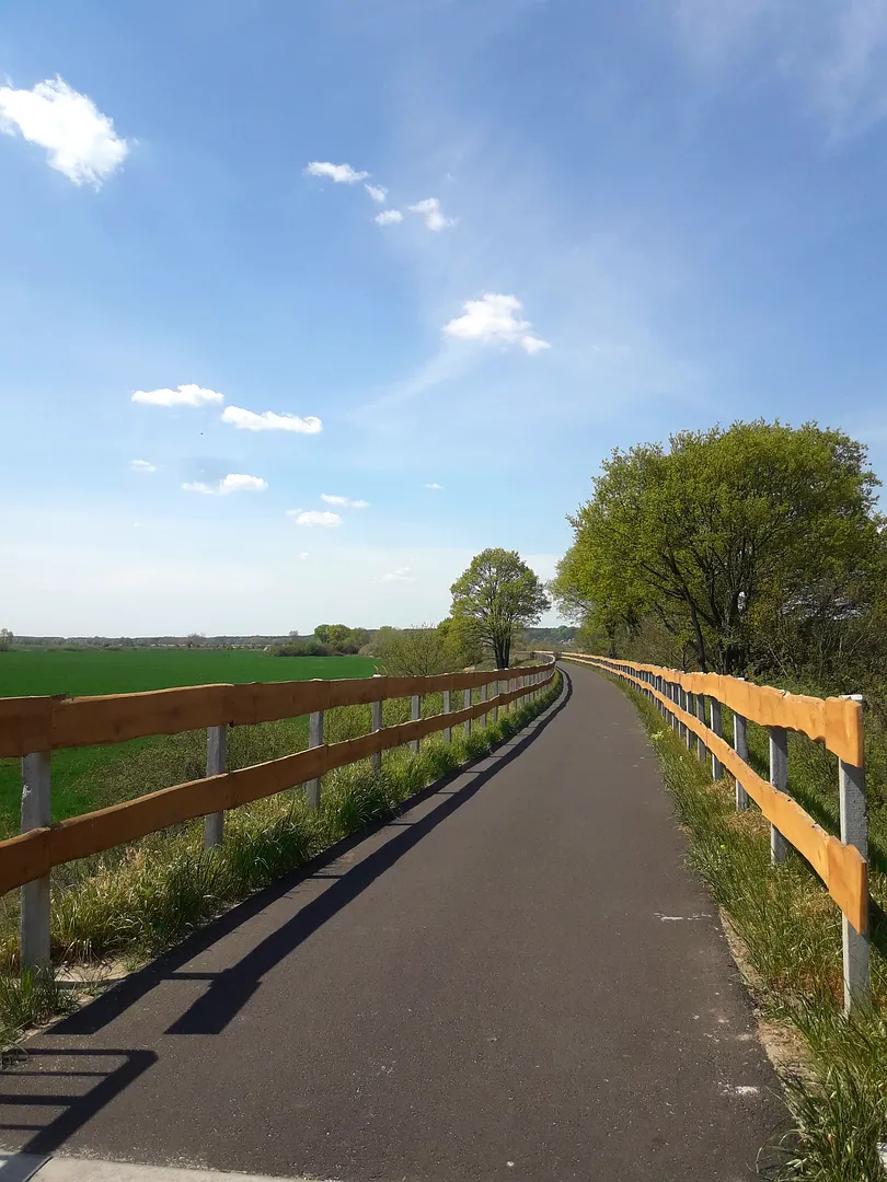 Paved cycling path between railings at Railway cycling route at Stany