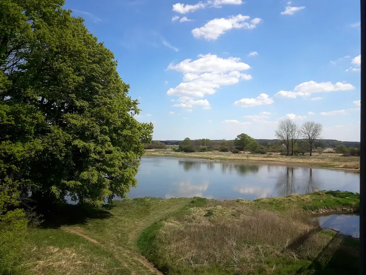 Water beyond the riverside bank at Railway cycling route at Stany