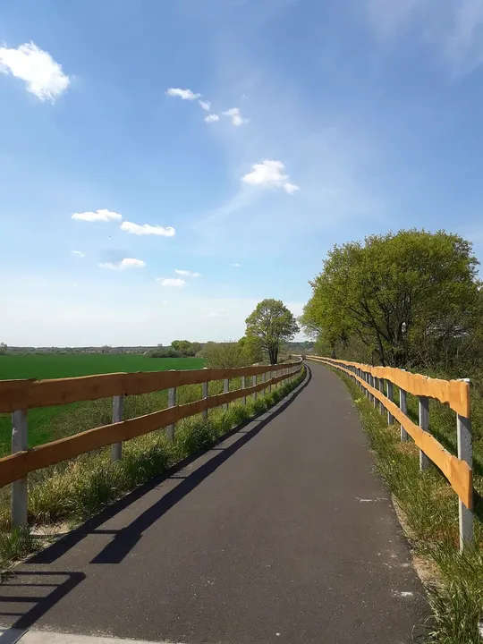 Paved cycling path between railings at Railway cycling route at Stany