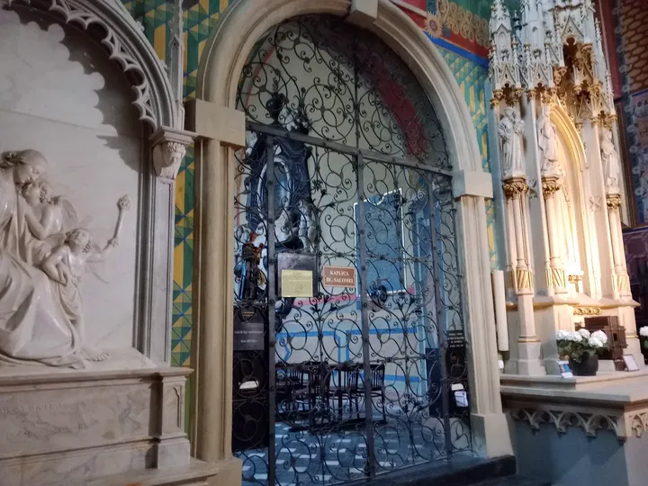 A metal grille and carved stone surround at Saint Francis of Assisi Basilica, Kraków