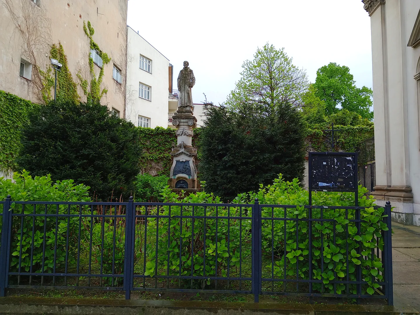 Saint Simon’s statue above its stone base and iron fence at Saint Simon of Lipnica statue