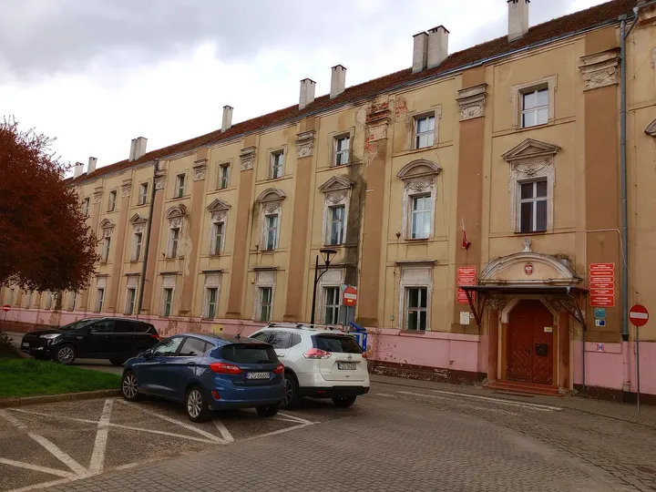 Long pale building and parked cars at Słowiański Square, Żagań