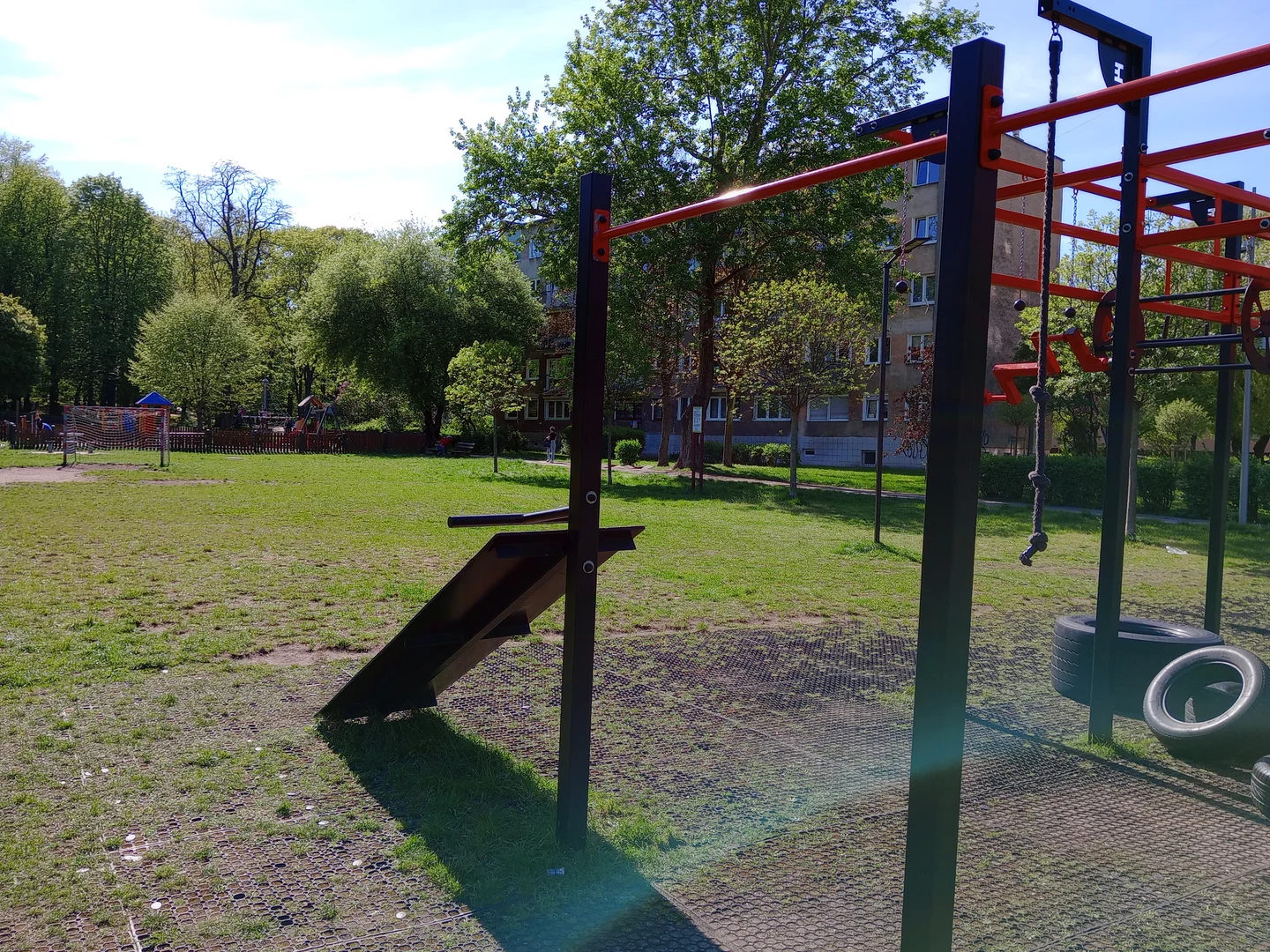 Red equipment beside the green park at Tysiąclecia Park outdoor exercise ground