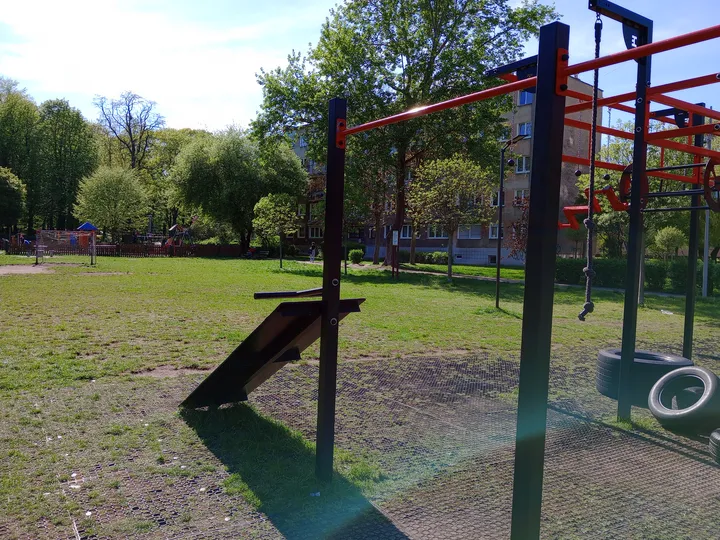 Red equipment beside the green park at Tysiąclecia Park outdoor exercise ground