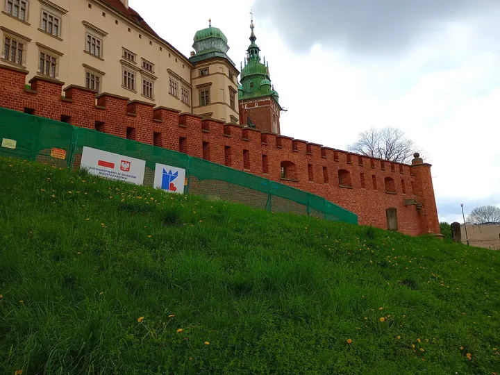 The outer walls rise above a grassy slope on Wawel Hill in Kraków