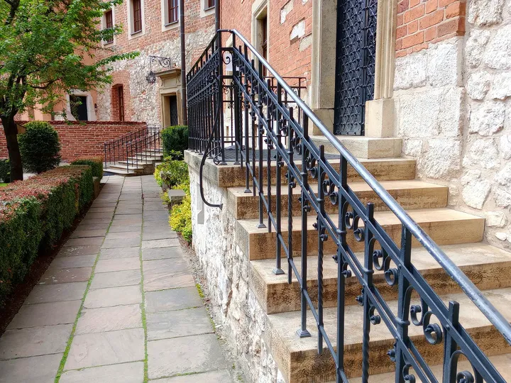 Stone entrance steps and a black iron railing beside a brick building on Wawel Hill