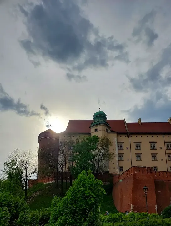 Castle walls, a tower and trees on the approach to Wawel Hill in the evening