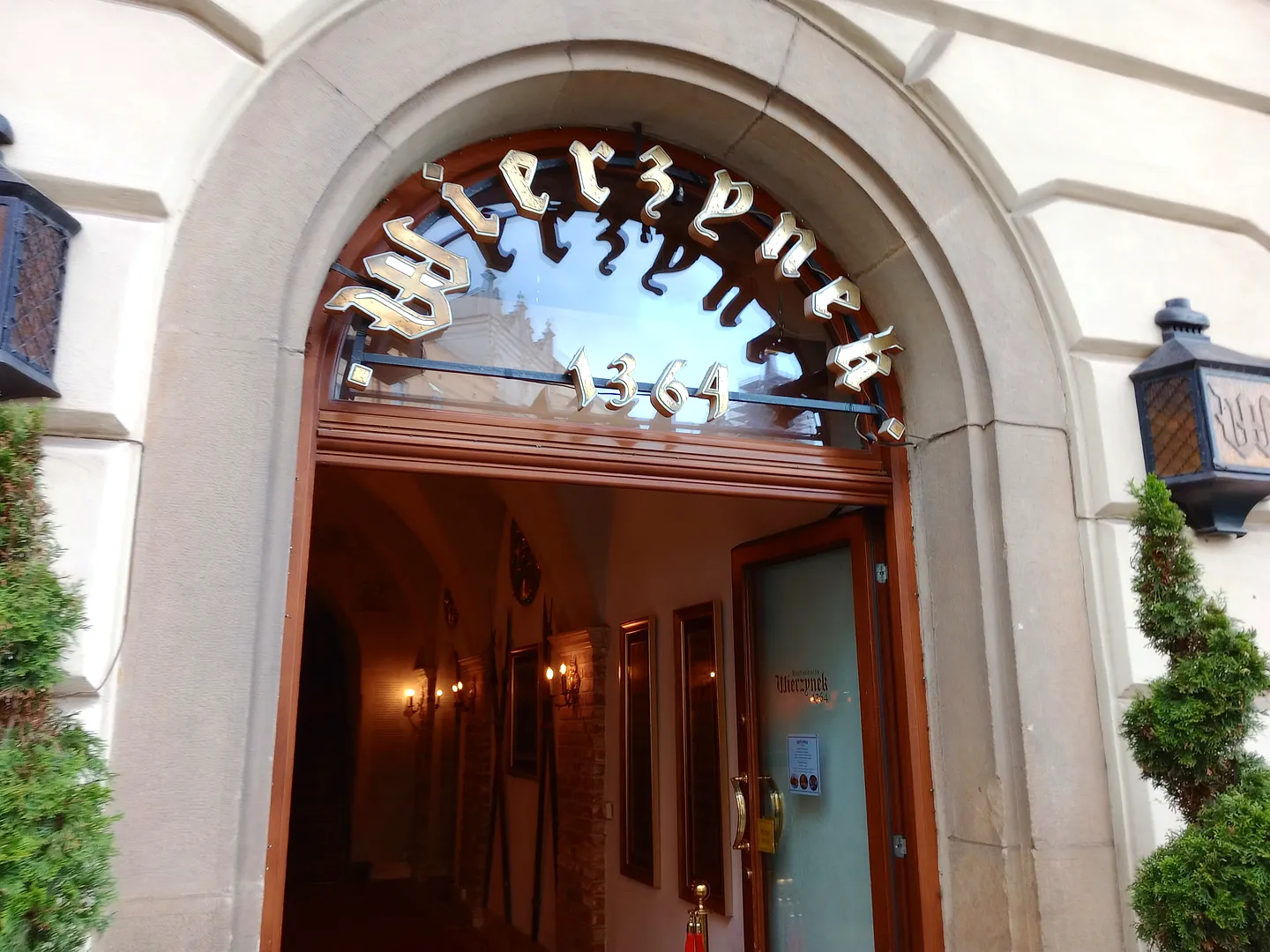 Lit entrance beneath a stained glass arch at Wierzynek