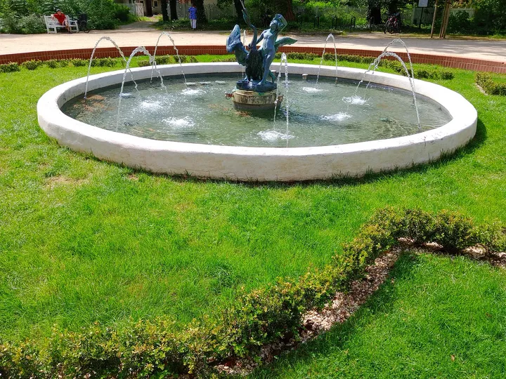 A circular fountain sits in the grass beside the palace paths in Zatonie Ducal Park